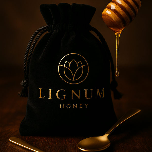 Black drawstring bag with 'Lignum Honey' logo, honey dipper, and spoons on a dark background